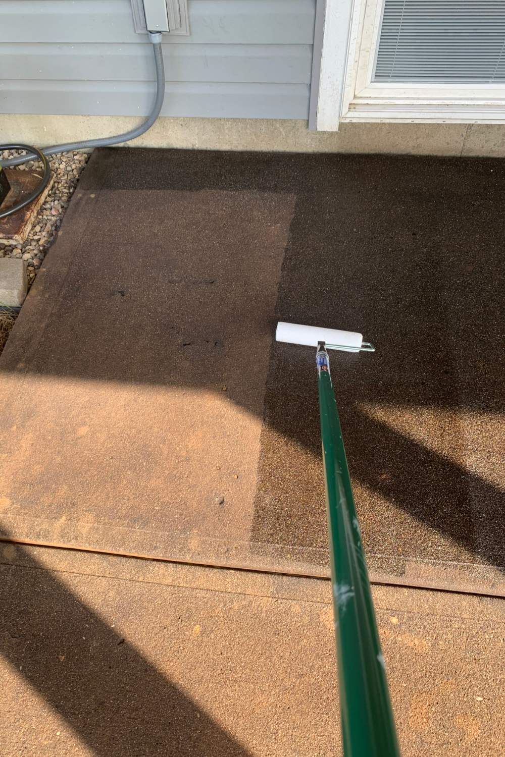 Concrete patio during the second coat of sealer application with a nap roller