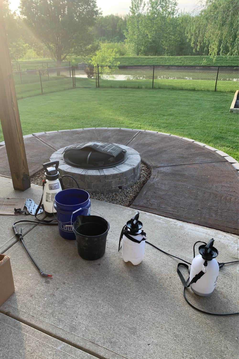 Concrete patio during the staining process with tools and supplies like sprayers and buckets