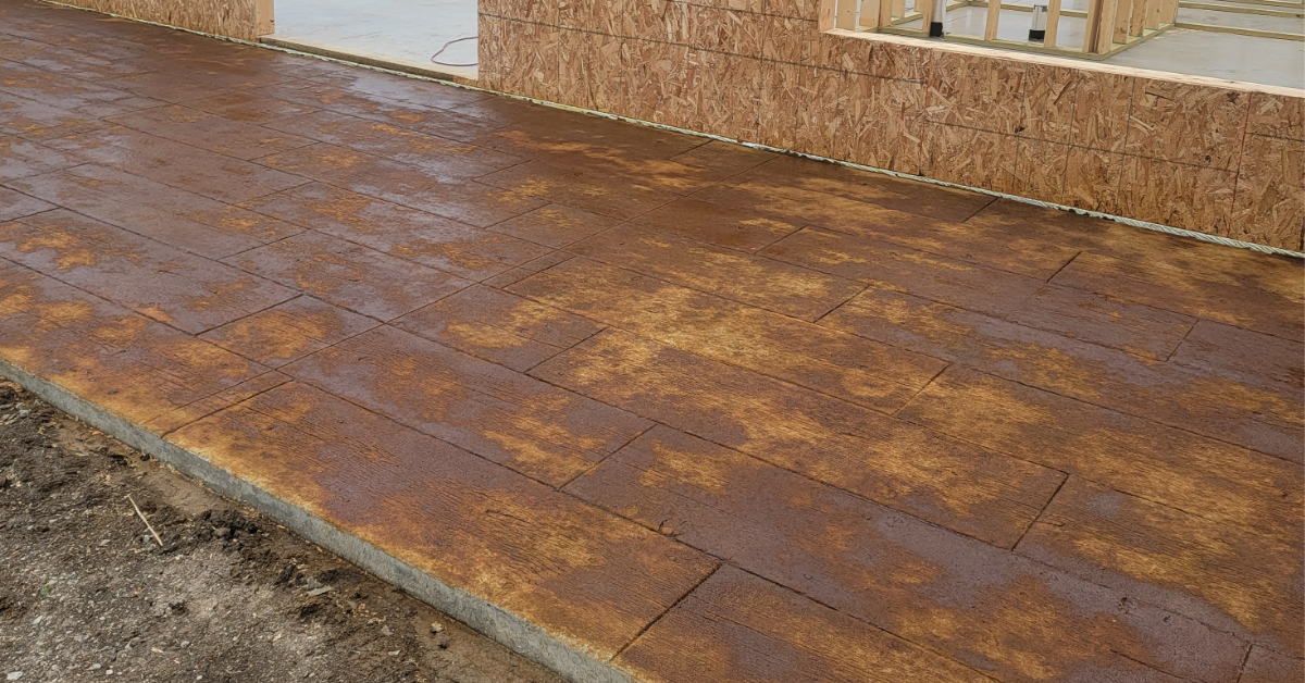 Stamped concrete patio with a wood plank design during staining