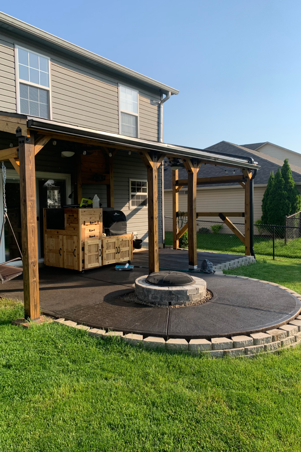 Fully stained and sealed circular patio complete with a dark, rich color, integrating with the lawn and outdoor setting