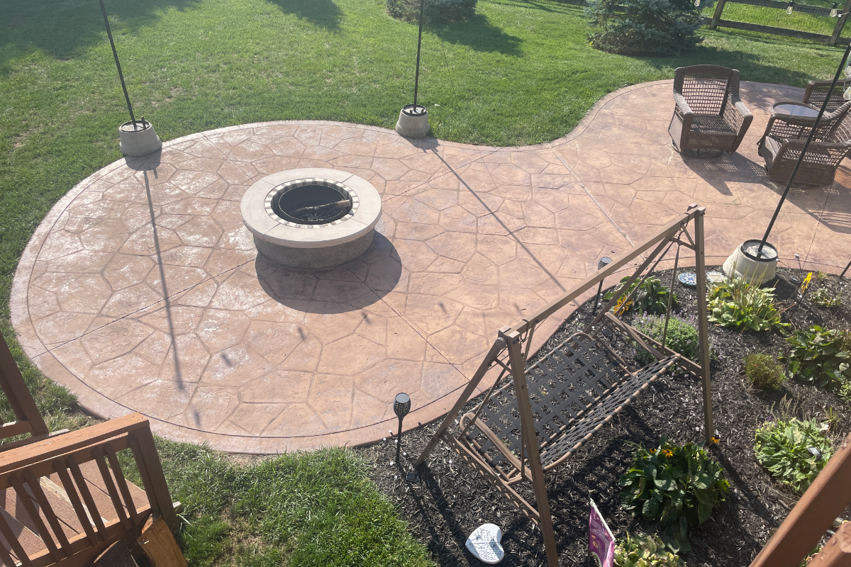 Antiquing - Patio - Before - Aztec - Stamped - Fire Pit Faded stamped concrete patio with fire pit before restaining, showing dull color and surface wear.