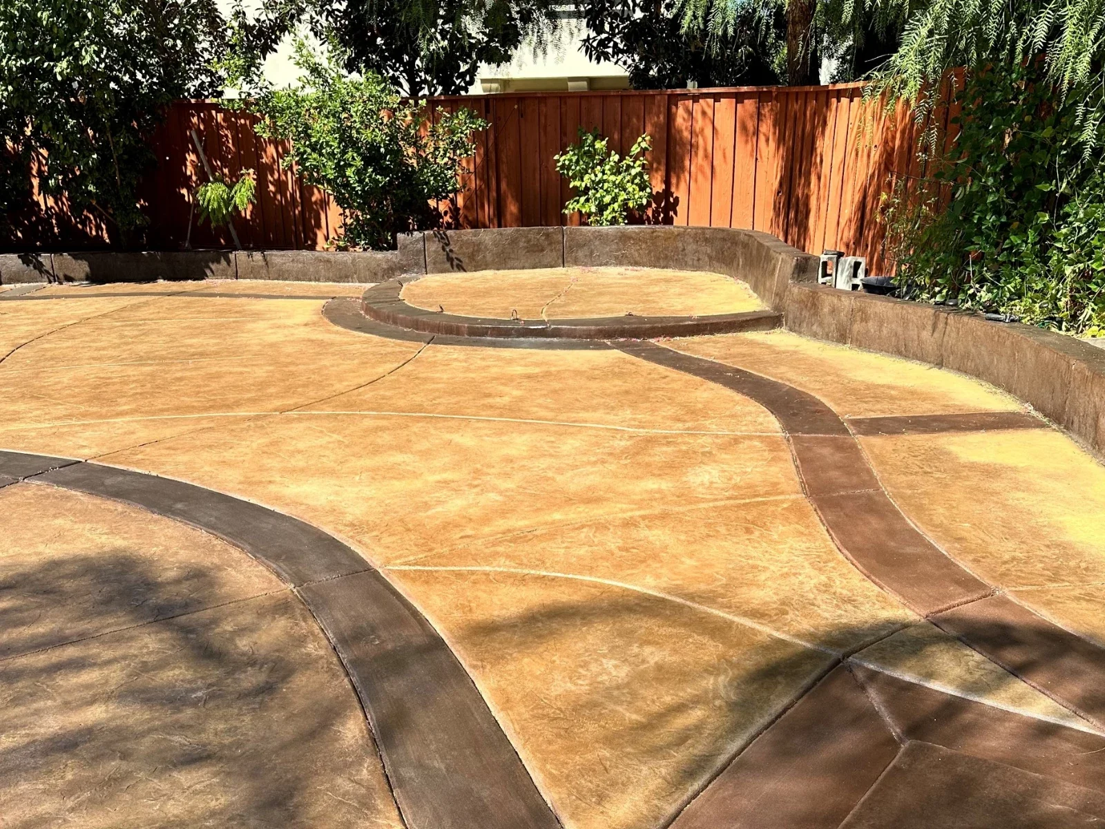 Backyard concrete patio refinished with Café Royale base color and Aztec Brown borders, creating a rich, uniform tone