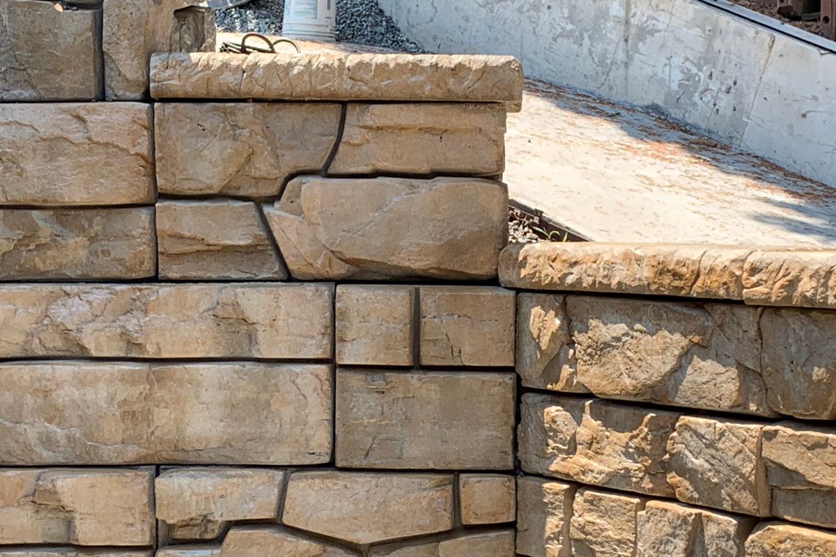 Retaining wall refinished with Caf Royale EasyTint Retaining wall finished with Café Royale EasyTint™ Satin, showing rich brown tones and natural stone texture.