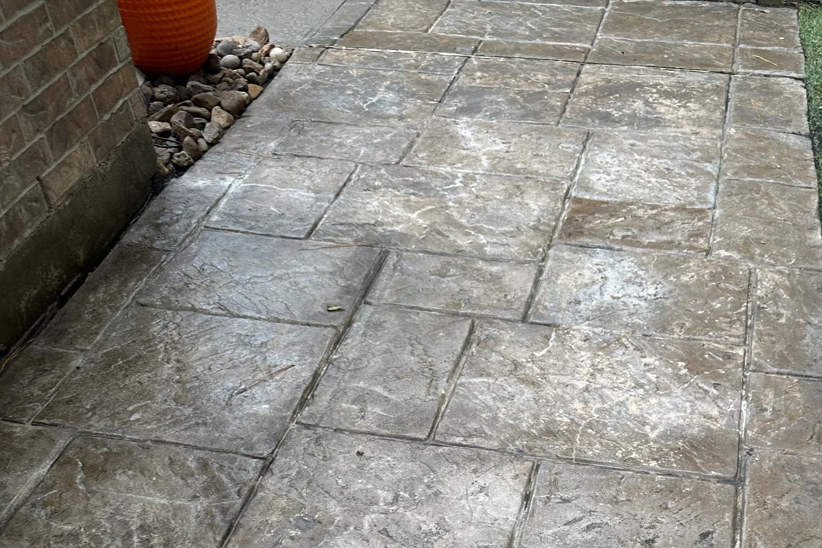 dull and faded stamped concrete walkway showing wear and discoloration iscolored and faded stamped concrete, showing signs of wear and age.