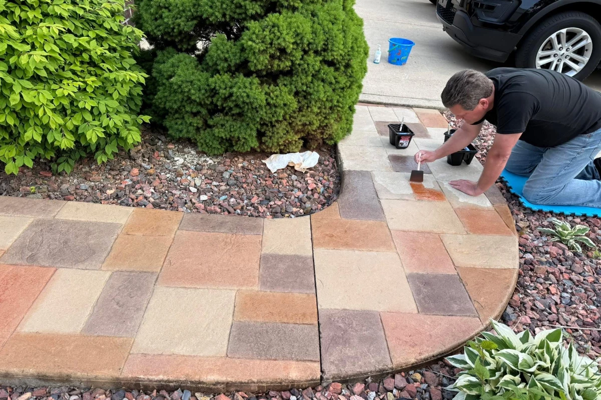 sponge-brush-application-antiquing-stain-auburn-khaki-terracotta-yukon-ashlar-pattern-walkway Homeowner applying Auburn Antiquing Stain with a brush to refresh faded stamped concrete walkway.