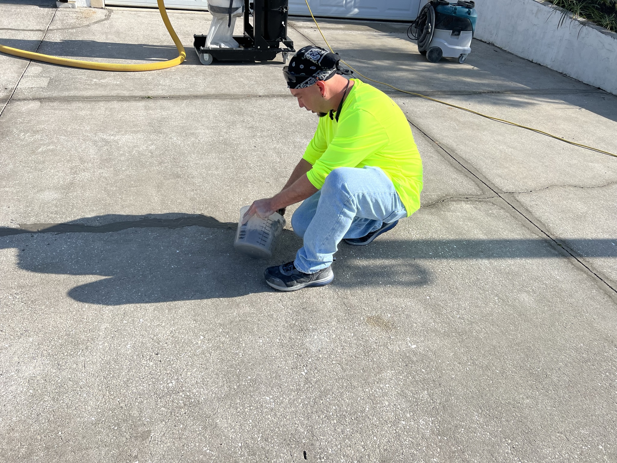 Tyler from CSI diligently patching concrete cracks to ensure a smooth, durable driveway surface