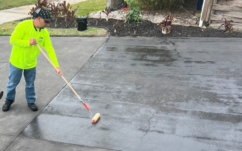 Contractor applying EasySeal satin with a roller over the Steel Gray ColorWave, ensuring a durable and protective finish for the modern concrete driveway