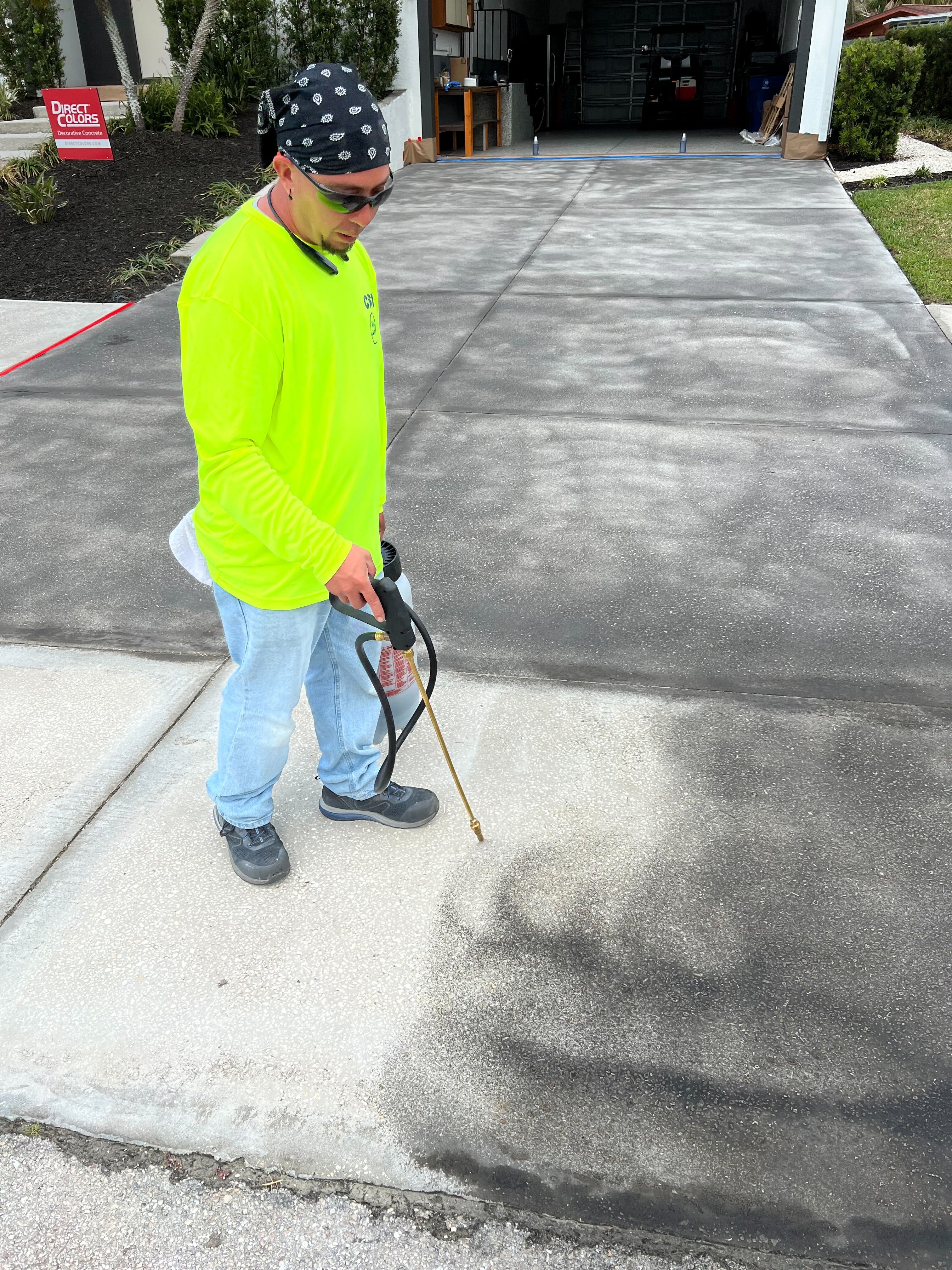 Tyler, the skilled contractor, masterfully applying ColorWave stain using a figure-8 pattern for seamless overlap and even color intensity on the driveway
