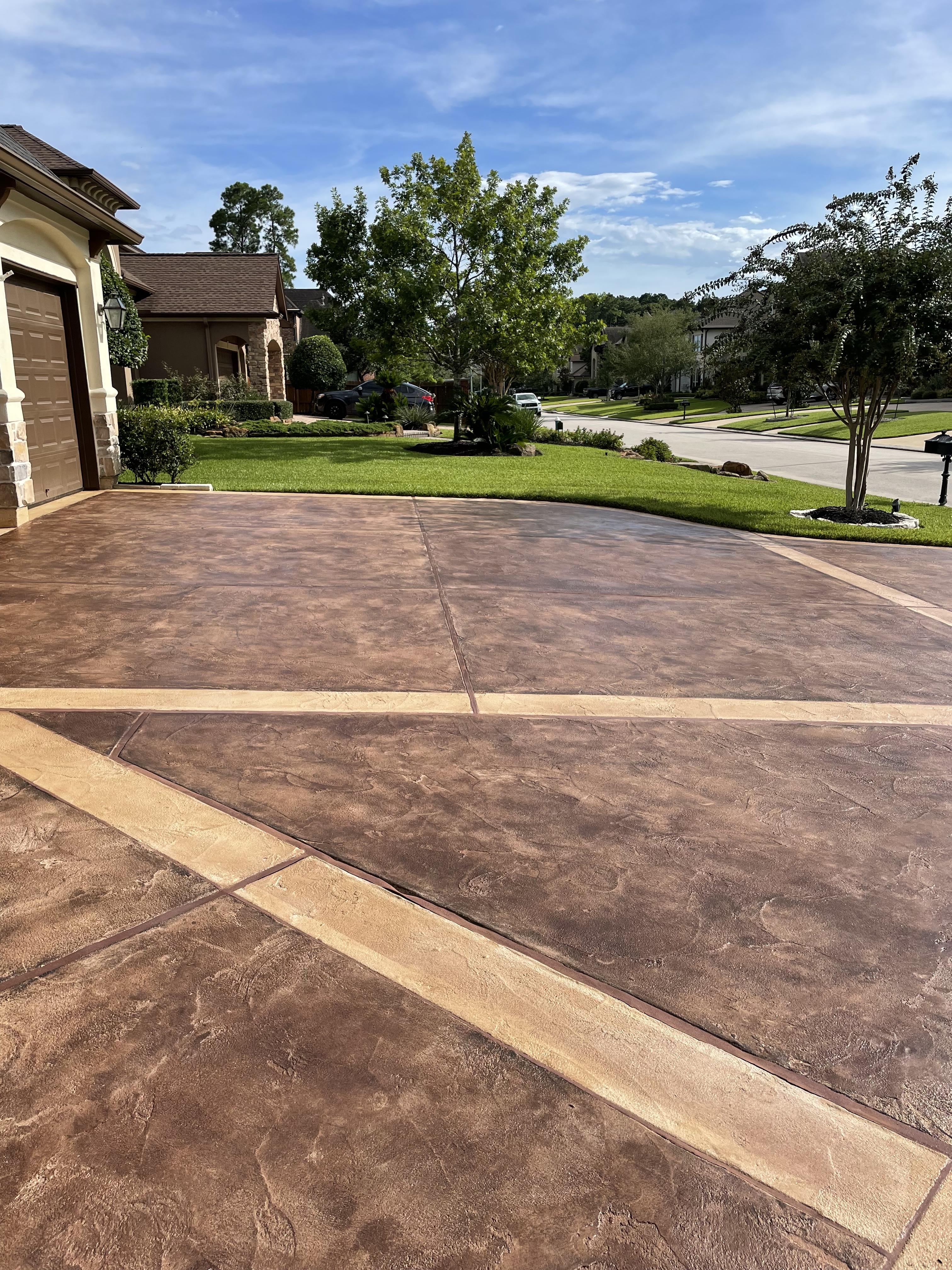 Driveway with a geometric design stained using a combination of Aztec Brown and Charcoal Antiquing stains. The stains have been carefully applied to create a modern and edgy design that enhances the texture and depth of the concrete surface.