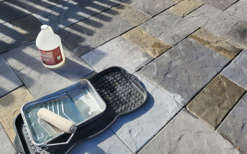 Image showing the process of sealing a textured, stamped concrete floor with a product labeled 'EasySeal', evident in the wet sheen on the surface and the EasySeal container in the background